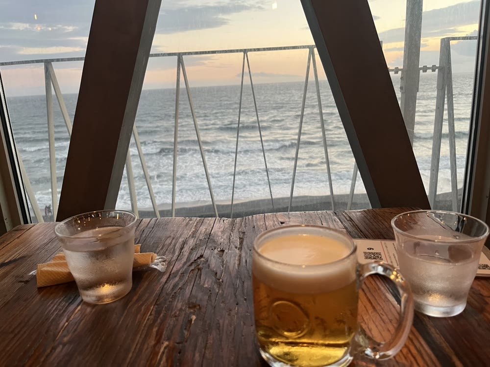 レストランの席から見た、夕方の七里ヶ浜の海と、ビール