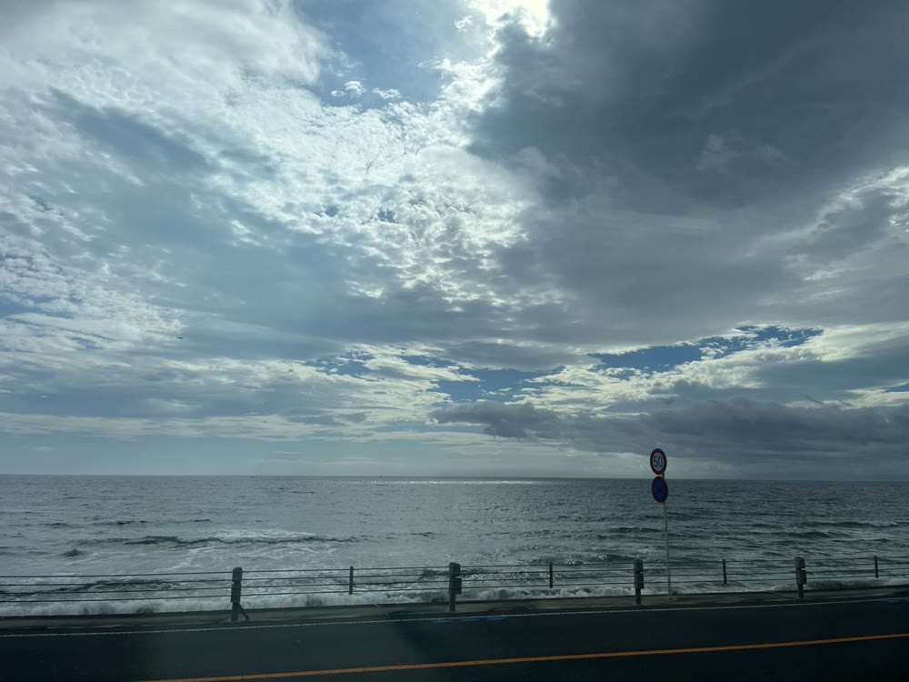 国道のガードレールの向こうに広がる、七里ヶ浜の海と雲
